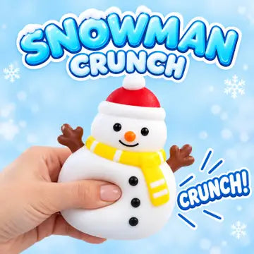 A hand holds a squishy snowman toy with a red Santa hat, yellow scarf, and brown twig arms against a light blue background with the text 'SNOWMAN CRUNCH' and 'CRUNCH!'.