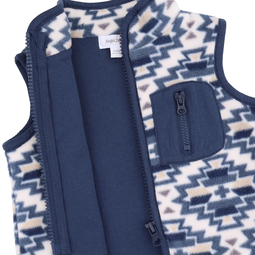 A close-up of a children's fleece vest with a navy blue front zipper, a zippered chest pocket, and a cream and navy geometric pattern on the sides.