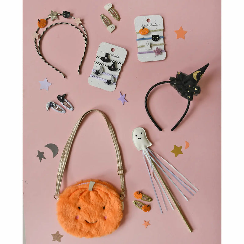 a fun flat lay shot of all the current Halloween products for Rockahula. pumpkin bag, with hat headband and fun hair clips and hair ties with witch hats and ghosts. 