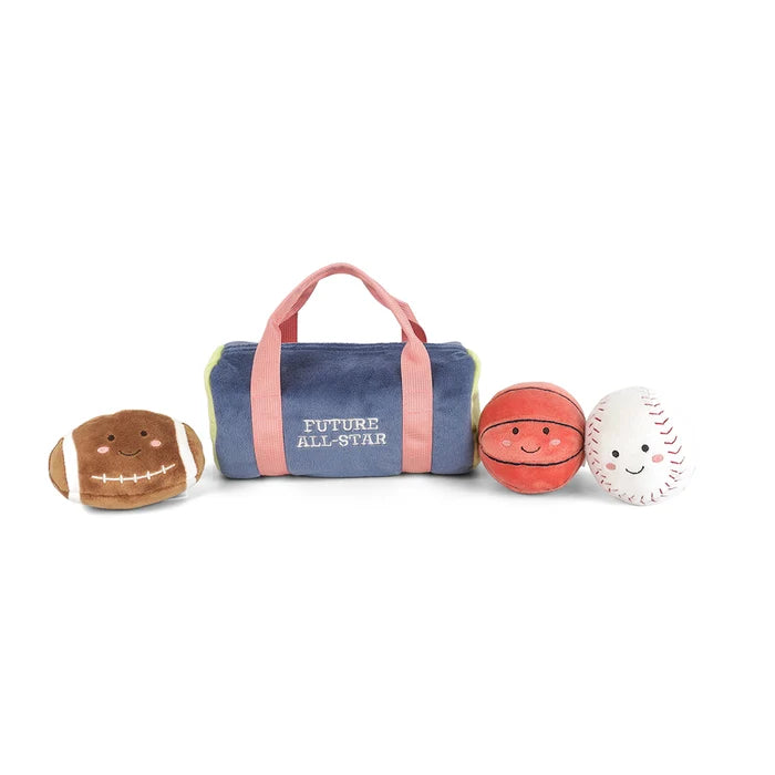 A plush toy duffel bag with pink handles and straps, featuring the words 'FUTURE ALL-STAR' in white. Three small plush sports balls are lined up in front of the bag: a brown football, an orange basketball, and a white baseball, all with embroidered smiling faces.