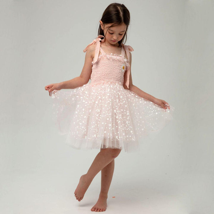 young girl modeling the tulle dress lifting the tulle up. pink stretchy slip under the dress. 