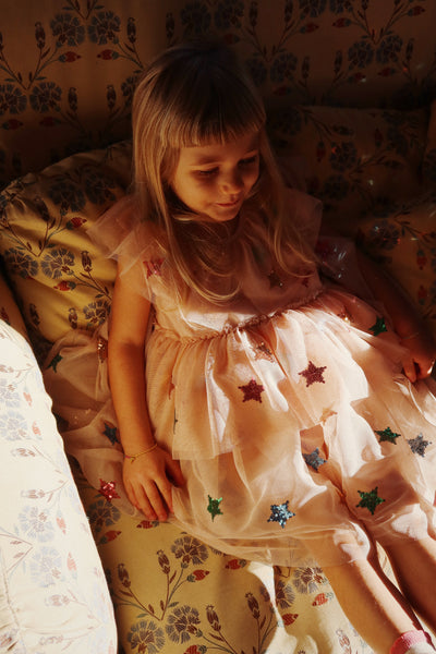 another view of the dress, this time the little girl is sitting on a couch lounging as her dress billows in the light. 