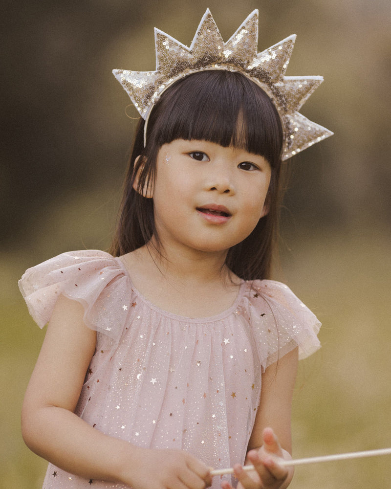 the dress is modeled on a young girl with gold crown