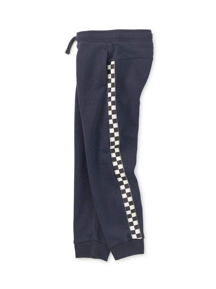 A pair of navy blue sweatpants featuring a black and white checkered stripe down the side, shown against a plain white background.
