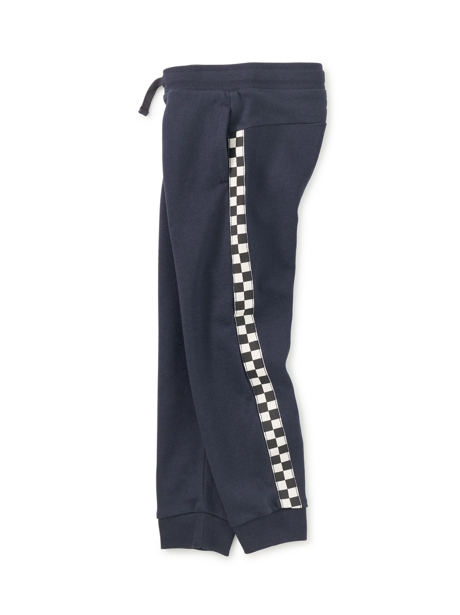 A pair of navy blue sweatpants featuring a black and white checkered stripe down the side, shown against a plain white background.