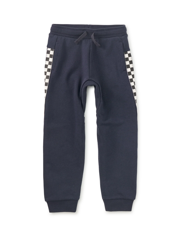 A pair of navy blue sweatpants with a black and white checkerboard pattern on the side pockets, featuring a drawstring waist and ribbed cuffs.