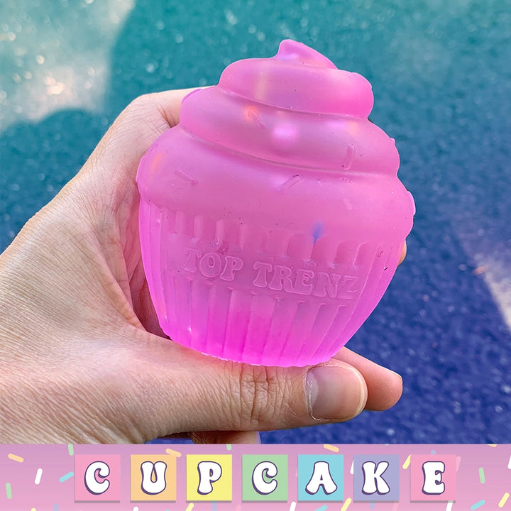 Pink cupcake-shaped toy held in a hand with a blue background