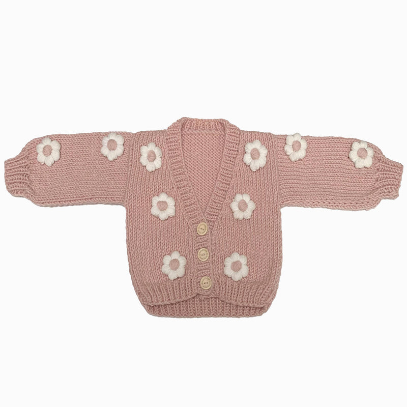 chunky pink cardigan with white daisies all over and three button closure. has the look and feel of a no closure cardigan. 