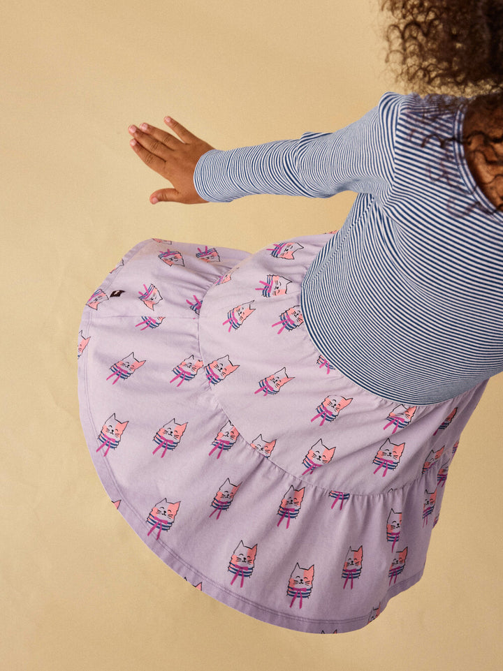 Child wearing a dress with a cat pattern on a beige background