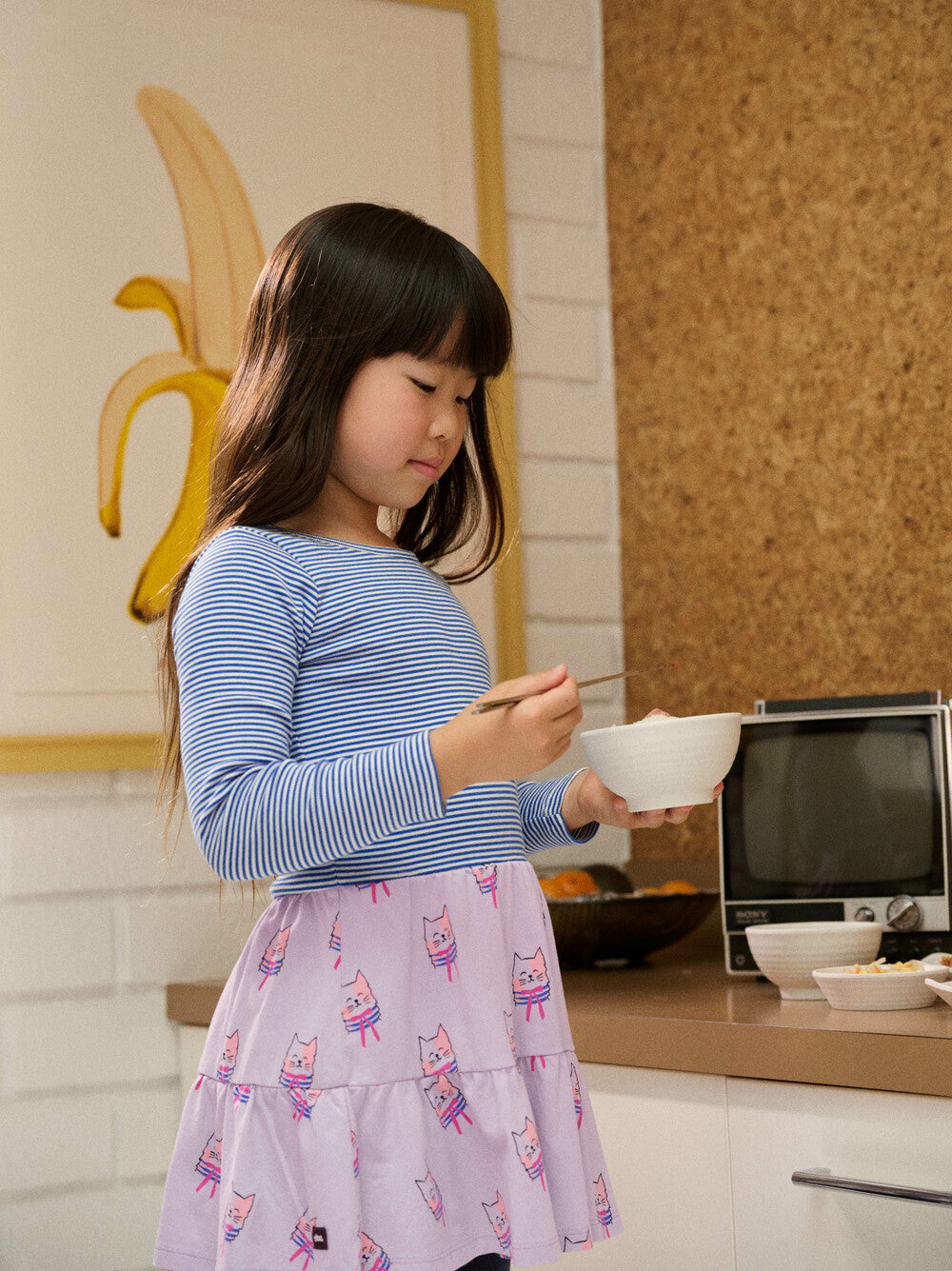 Young girl in a kitchen holding a bowl and spoon