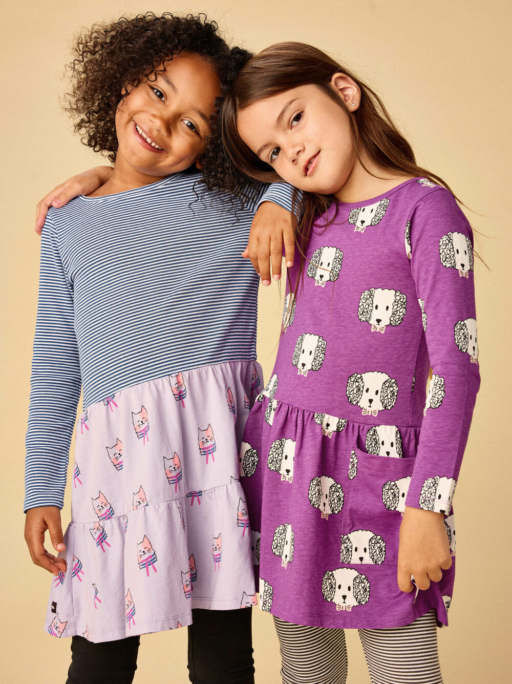 Two children wearing patterned dresses on a beige background