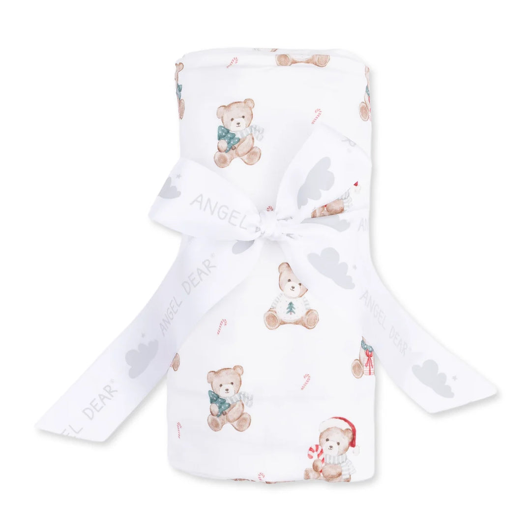 A white baby blanket or swaddle with a teddy bear and candy cane pattern, tied with a white ribbon printed with the brand name 'Angel Dear'.
