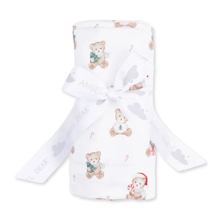 A white baby blanket or swaddle with a teddy bear and candy cane pattern, tied with a white ribbon printed with the brand name 'Angel Dear'.