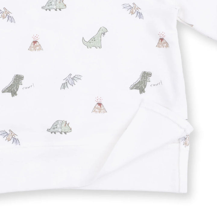 White long-sleeve baby garment with a repeating dinosaur and volcano print, shown folded with a soft corner turned over.