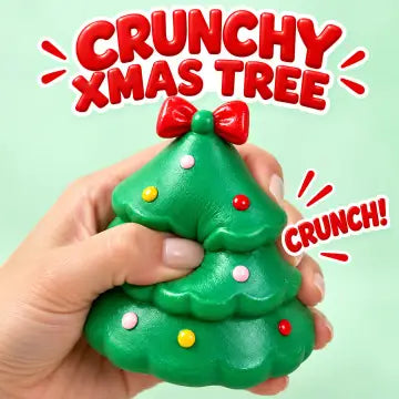 A hand holding a green Christmas tree squishy toy with a red bow and colorful ornaments, with text overlays reading 'CRUNCHY XMAS TREE' and 'CRUNCH!' on a light green background.