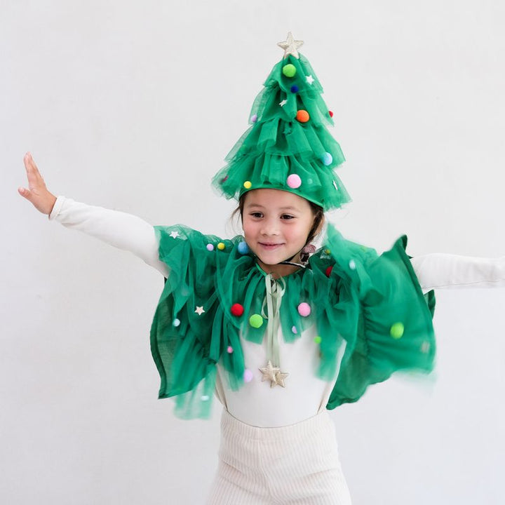 Child wearing a green Christmas tree costume with colorful decorations on a white background