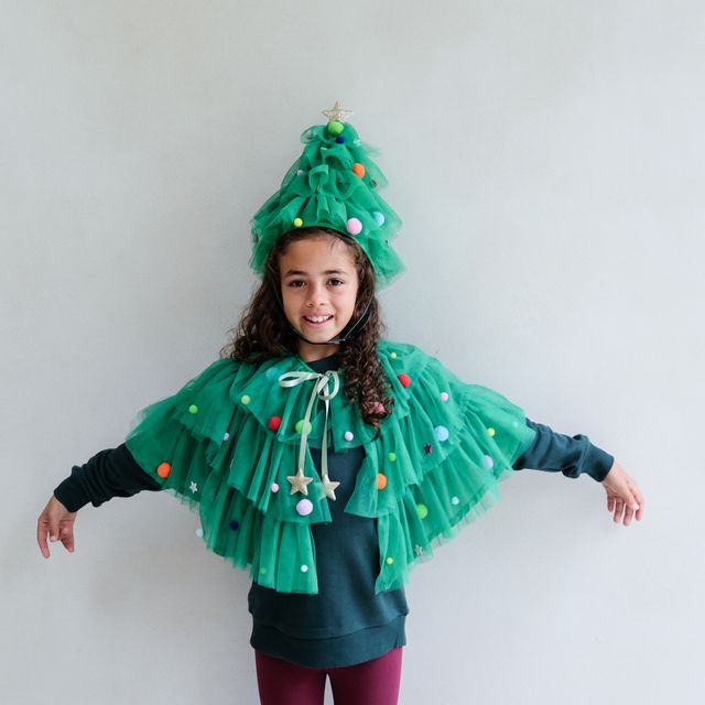 Person wearing a festive green costume with a tree-like design on a plain background