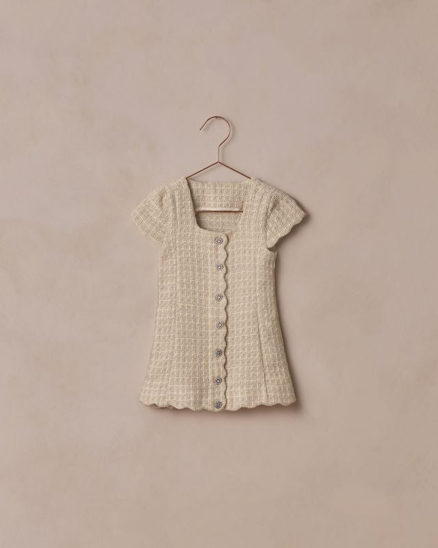 Beige textured dress on a hanger against a beige background