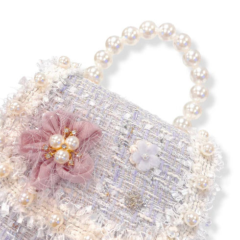Decorative purple tweed  handbag with pearls and pink flower on a white background