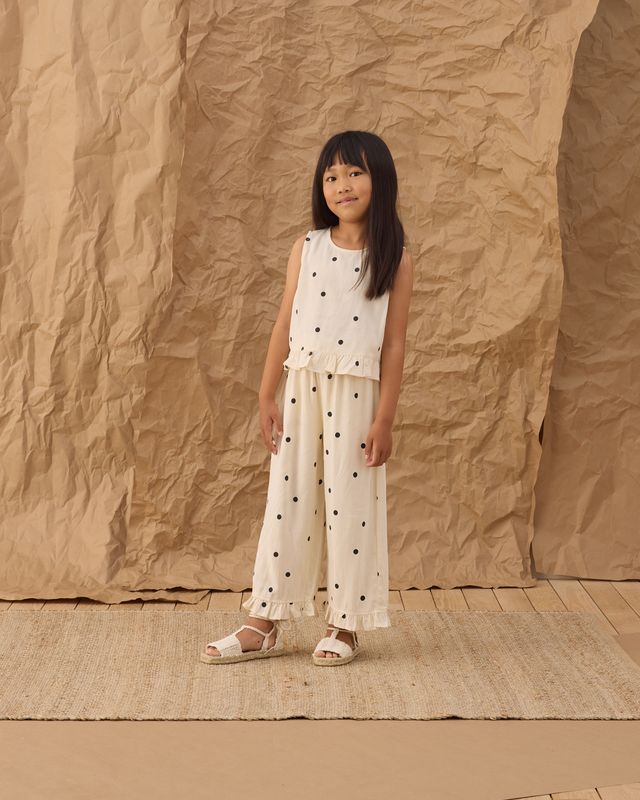 young girl wearing a white polka top and wide leg bottoms. 