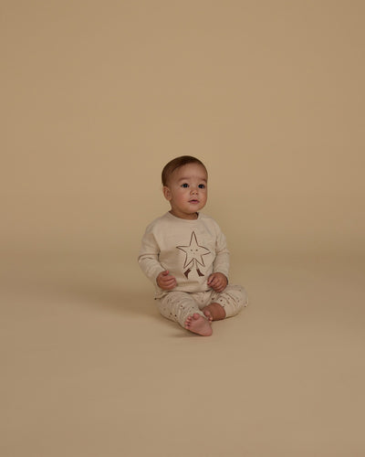 little baby modeling the twinkle set. tan star on the shirt and tiny little stars all over the pants. 