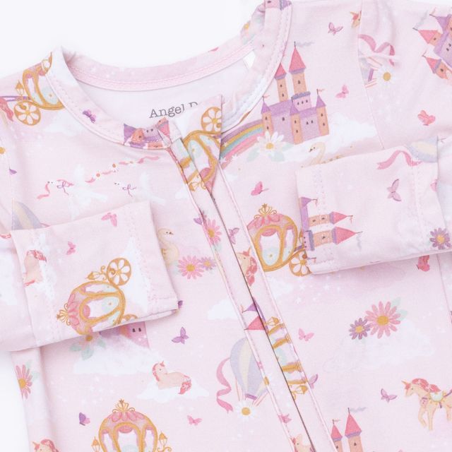 the top of a baby footie with the print of unicorns, princesses and dragons. 