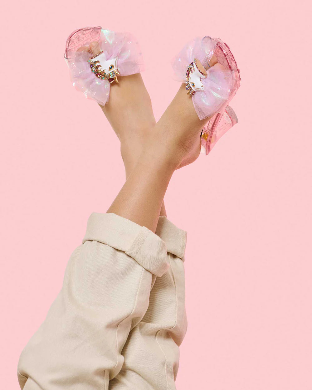 a young girl modeling the pink slip on shoes with a pink tulle bow and an enamel unicorn clip