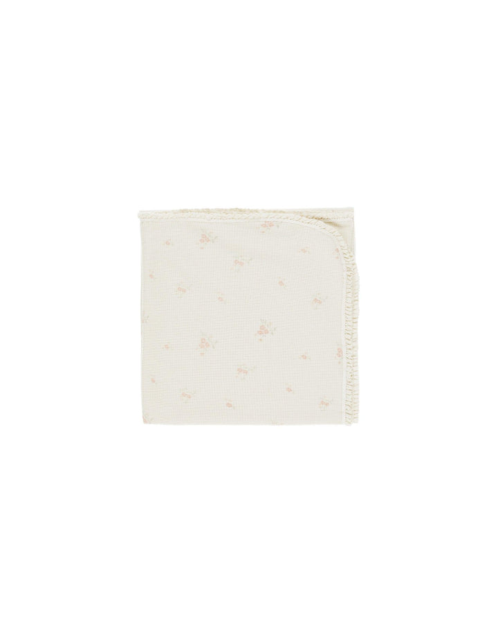 beige blanket with tiny pink rosebuds on it. 