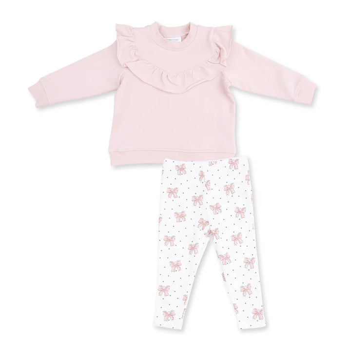 A toddler girl's two-piece clothing set featuring a light pink long-sleeve top with a ruffled collar and white leggings with a pink bow and polka dot pattern, laid flat on a white background.