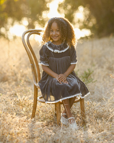 Little girl modeling the midnight gray velvet dress with big collar and lace trim on sleeves and collar. 