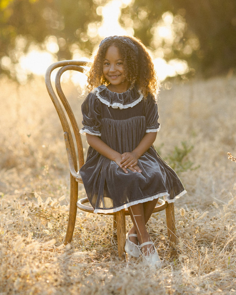 Little girl modeling the midnight gray velvet dress with big collar and lace trim on sleeves and collar. 