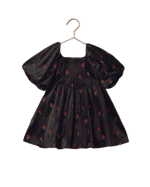 Black dress with floral pattern on a beige hanger against a beige background