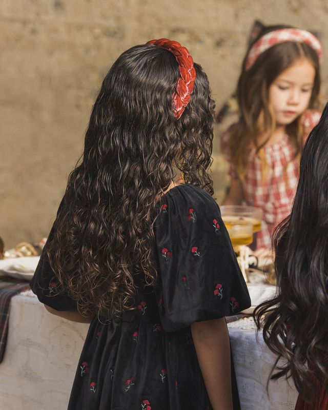 Girl with a red headband looking at herself in a mirror