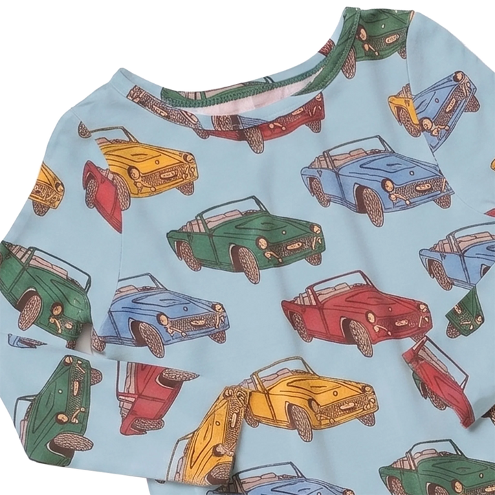 A close-up of a light blue long-sleeve top with an all-over print of vintage convertible cars in green, blue, red, and yellow.
