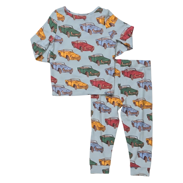 A two-piece children's pajama set featuring a light blue long-sleeve top and matching pants, both covered in an all-over print of colorful vintage cars.