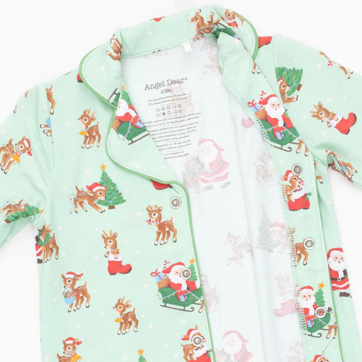 A mint green zippered pajama shirt with a festive Christmas print featuring Santa Claus, reindeer, and Christmas trees, shown flat on a white background.