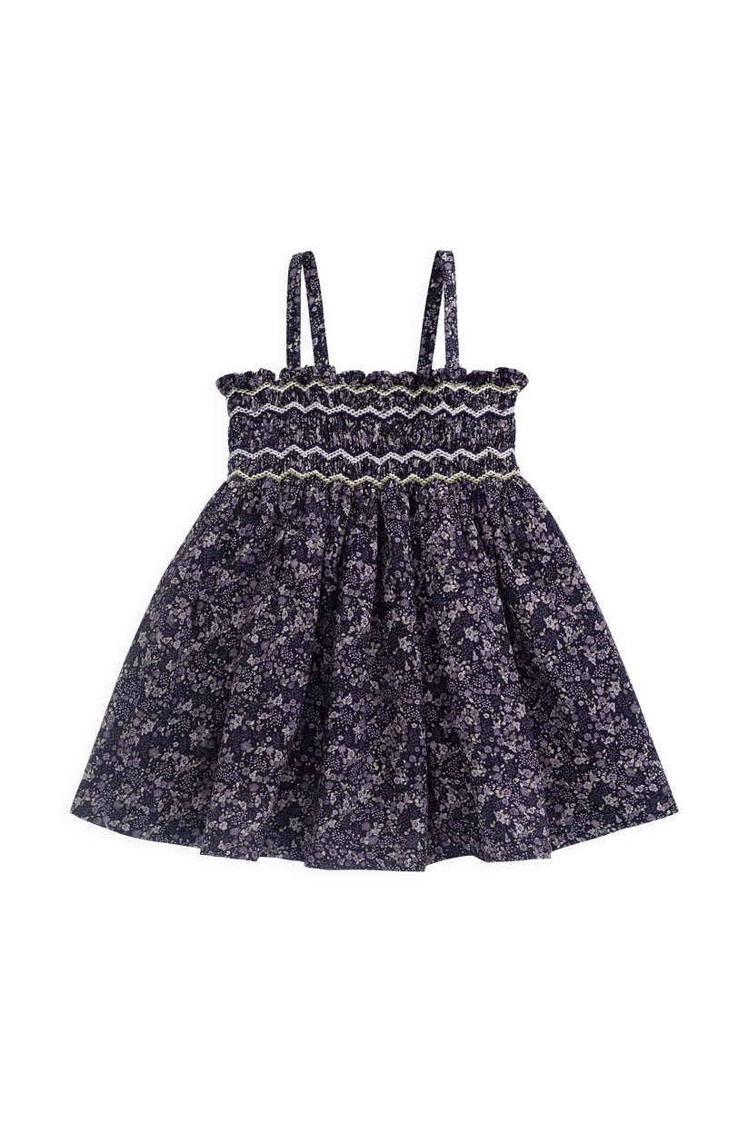 A toddler girl's sleeveless dress with a smocked bodice and a flared skirt, featuring a dark navy blue and white floral pattern.