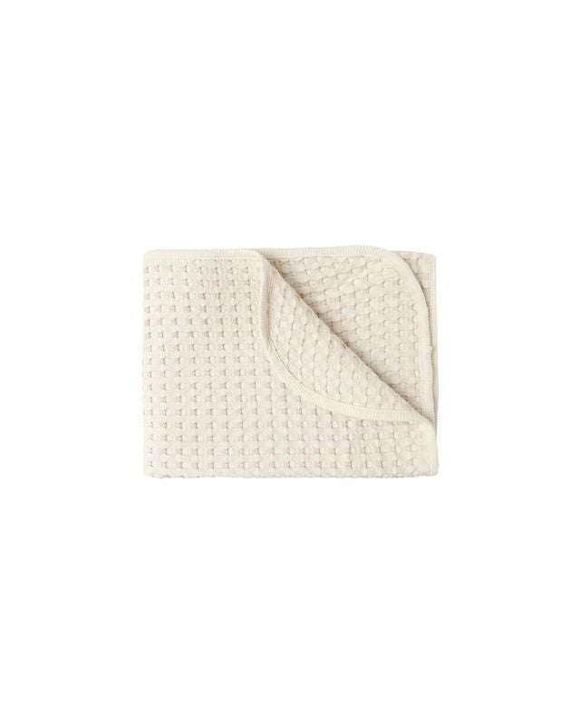 Beige textured waffke blanket on a white background