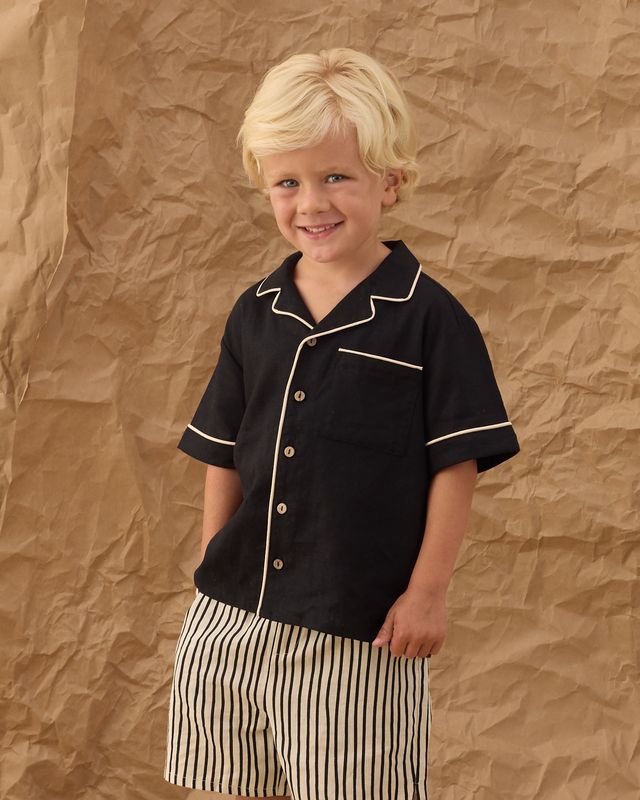 little boy wearing a black button down shirt and black and white striped shorts 