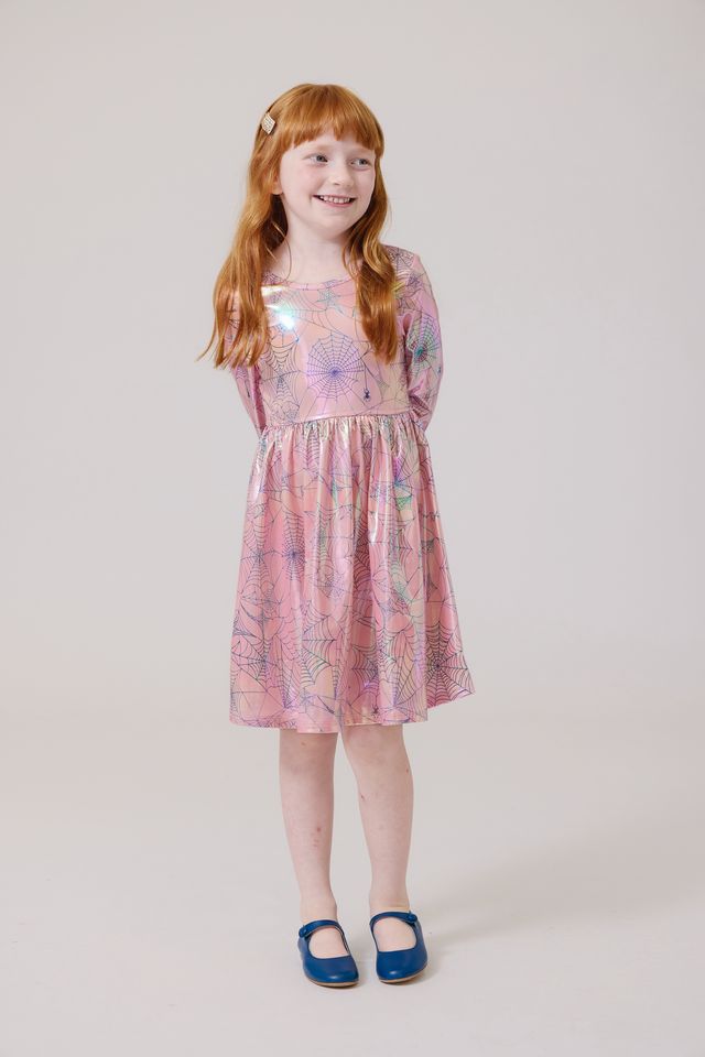 Young girl wearing a pink  dress with spider webs on it on a white background