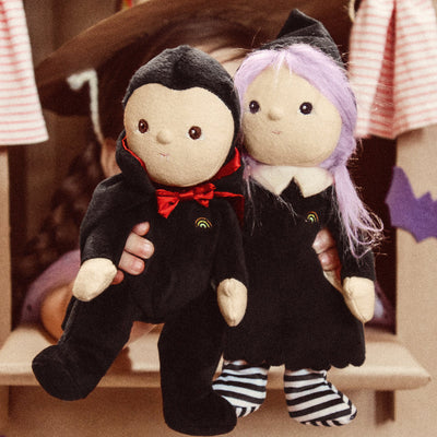 two dolls- one vampire with cloak and fangs and red bowtie. one witch with lavender hair and striped socks. 