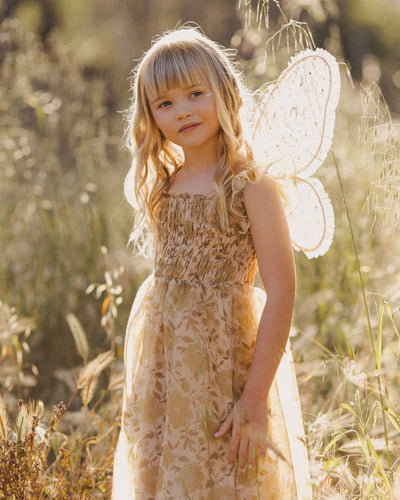 young girl modeling the wings in a beautiful afternoon light. Young girl is wearing a Fall dress with the champagne wings with gold stars.  