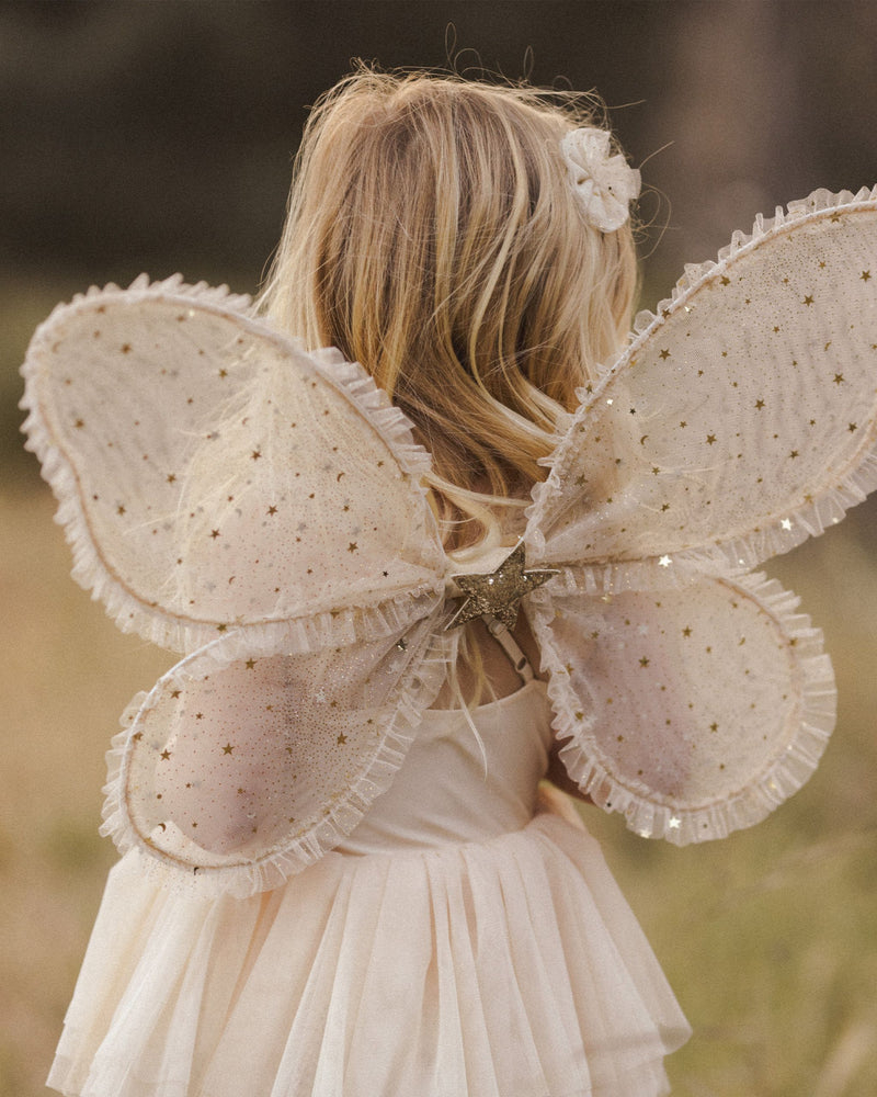 close up of the wings modeled on a young child in a beautiful afternoon light. wings are beige tulle with ting glitter gold stars.