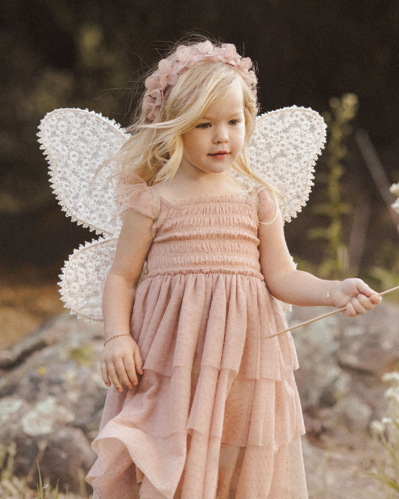 young child modeling the wings with the daisy print as she runs around in a Fall dusty rose dress. 