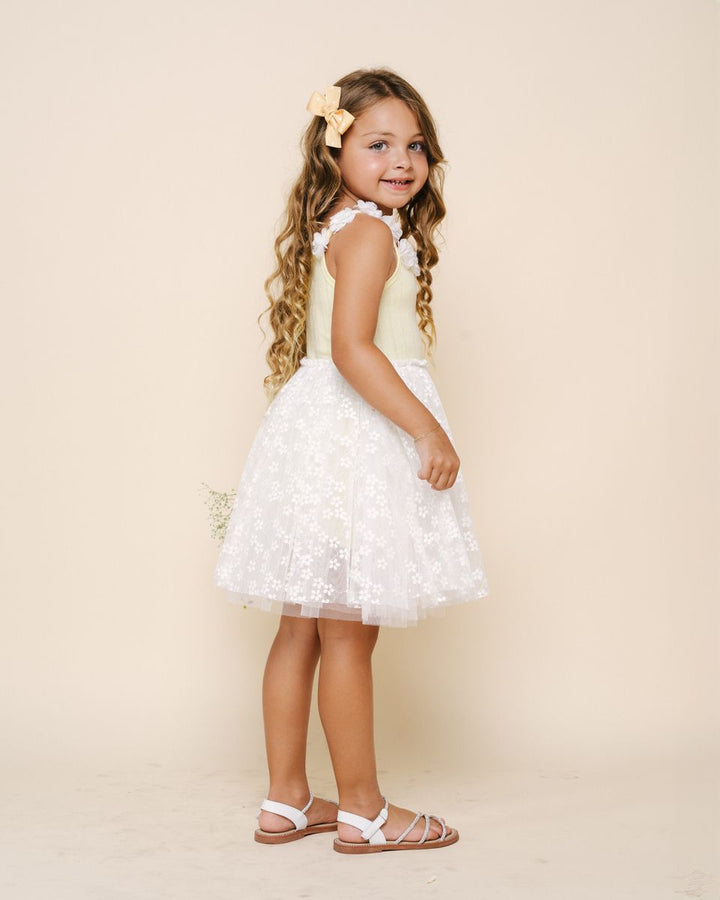 Young girl in a white dress with floral details against a beige background