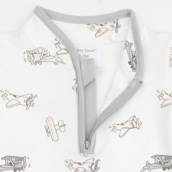 Close-up of a baby garment with a light gray zipper and trim, featuring an off-white fabric printed with small vintage airplane illustrations. The brand name 'Goi Deer' is visible on the inner neck label.