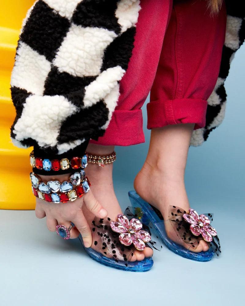 little girl trying them on her feet, showing how dramatic and glam they look on someone's foot given the clear top and embellishment of the shoe